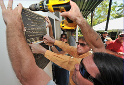 Mike Ruffo, right, drills into the front wall of the Ernest Hemingway Home & Museum Sunday, March 14, 2010, to fasten a Literary Landmark plaque to the house in Key West. Kris Niehouse, left, and Mike Morawski, center, help support the sign. Photos by Rob O'Neal/Florida Keys News Bureau